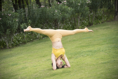 在公园草地上练瑜伽的亚洲年轻女人,倒立一字马