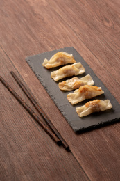 红褐色木板桌面上，石岩板上的煎饺