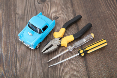 桌子上蓝色的小汽车模型和钳子及改锥等修车工具
