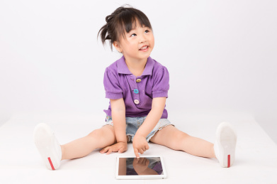 坐在地上表情开心手指平板电脑的小女孩