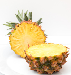 白色碟子上一个切开的金钻凤梨（无眼菠萝）