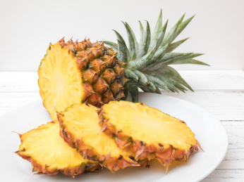 白色碟子上一个切开的金钻凤梨（无眼菠萝）