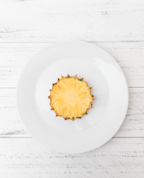 白色碟子上一片切开的金钻凤梨（无眼菠萝）横切面