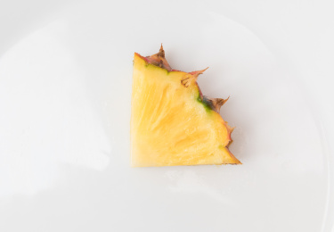 白色碟子上一块切开的金钻凤梨（无眼菠萝）