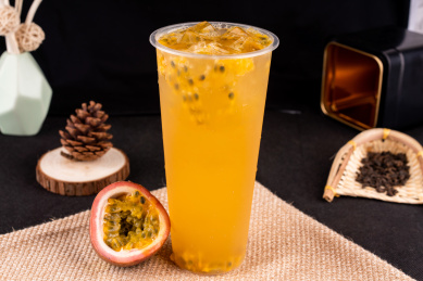 黑色背景下的装在塑料杯里的百香果柠檬茶
