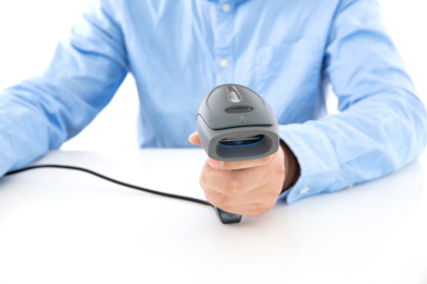 白背景前穿着蓝色衬衣的男性手拿扫码枪