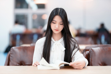   漂亮的女生坐在图书馆书桌前看书