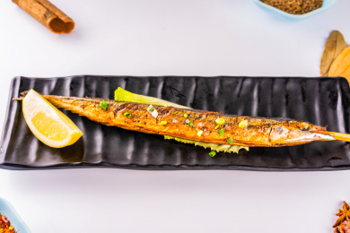 黑色盘里的一条烧烤秋刀鱼