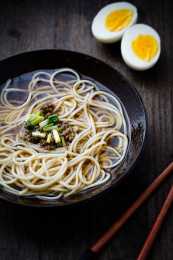 放在黑色陶碗里的亚洲中式面条和切开的鸡蛋