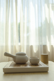 两杯热茶和一杯茶壶摆放在靠窗户的木桌上