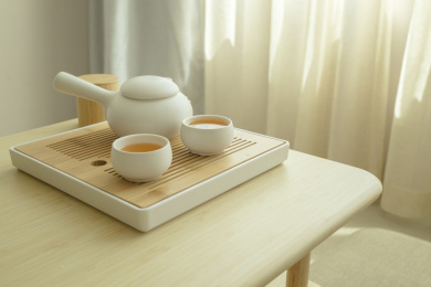 两杯热茶和一杯茶壶摆放在干净的木桌上