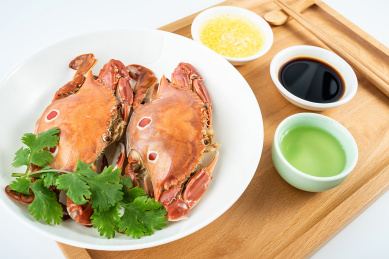 一碟清蒸三点蟹和调味酱料酒水在木托盘