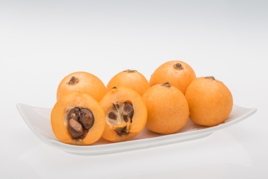 白色背景下白色长碟里的黄色枇杷果