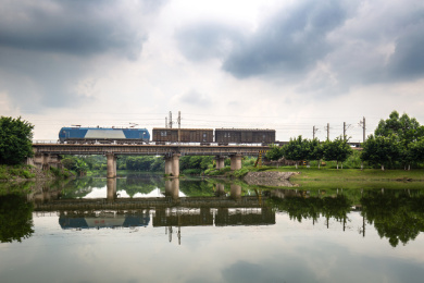 一辆火车从中国广东省东莞市燕岭湿地公园湖上的铁路桥上经过