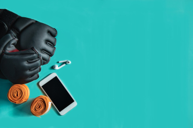 正上方视角蓝色背景特写格斗手套，绷带，手机和运动耳机