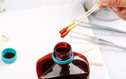 一只手拿着蘸过碘伏消毒液的两个棉签