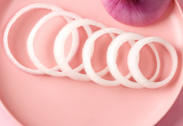 粉色盘子里有序摆放的切开的洋葱圈