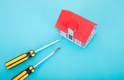 蓝色背景上一个小房子模型和一把改锥工具