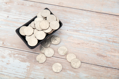 桌子上盛满美元硬币的小碟子和散落的硬币