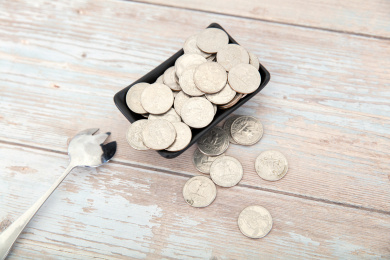 桌子上盛满美元硬币的小碟子和一把勺子