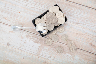 桌子上盛满美元硬币的小碟子和一把勺子