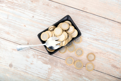 桌子上盛满欧元硬币的小碟子和一把勺子