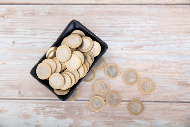 桌子上盛满欧元硬币的小碟子和散落的硬币