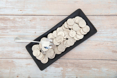 桌子上一个盛满美元硬币的盘子和一把钢勺