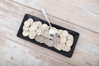 桌子上一个盛满美元硬币的盘子和一把钢勺