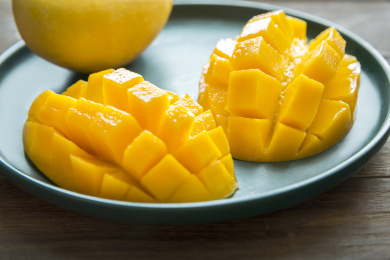 特写切好的芒果放在木桌上的绿色盘子里里