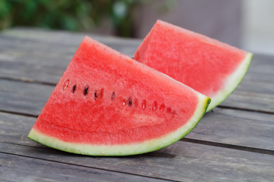 两片切好的西瓜放在户外的旧木桌上面