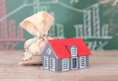 金融黑板前被铁链拴住的钱袋子和小房子模型