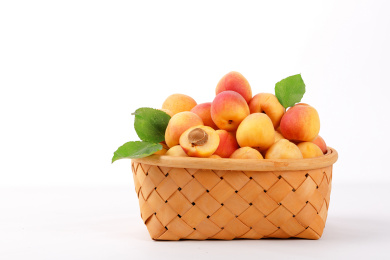 白底上一竹筐新鲜带叶子的水果——杏