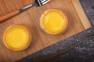 两个金黄色的港式蛋挞放在桌面上