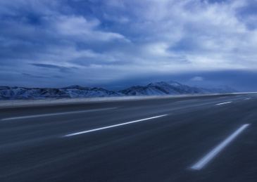 傍晚从雪山前穿过的一条速度感柏油路，中国西藏
