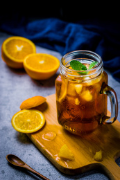 放在木砧板上冰红茶和散落的切开的甜橙