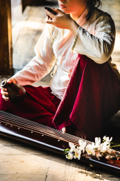 身着汉服女子坐在古代中式房子阳台上拿着酒杯酒壶喝酒地上放着一把古琴