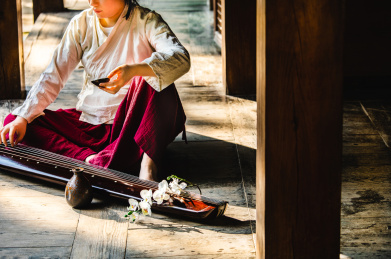身着汉服女子坐在古代中式房子阳台上拿着酒杯喝酒弹古琴