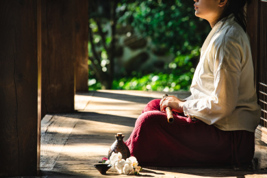 身着汉服女子坐在古代中式房子阳台上手里握着洞箫，旁边放着酒壶酒杯和兰花