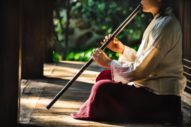 身着汉服女子坐在古代中式房子阳台上吹奏洞箫