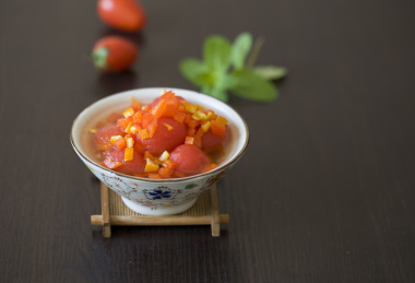 放在深色餐桌上的一碗中国传统家常凉拌菜 —  陈皮蜂蜜圣女果