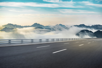 一条公路横穿在夏天清晨的郊区，山上有云海