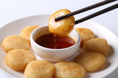 圆盘里的筷子夹着的金黄色油炸小糍粑