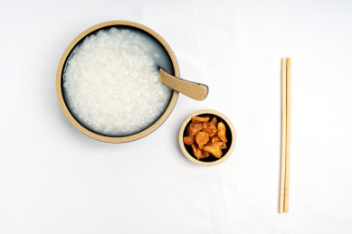 白色桌面上的中国广东风味美食——一碗白粥和一碟萝卜干