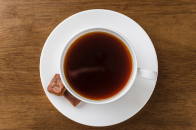 骨瓷茶杯里的红糖茶水和古法工艺制作的红糖块
