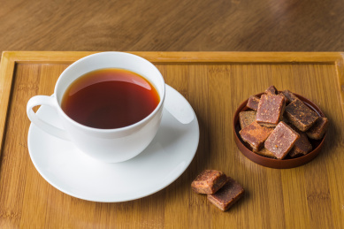 骨瓷茶杯里的红糖茶水和古法工艺制作的红糖块