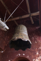 寺庙红墙角落的房顶挂着一口古代的大撞钟