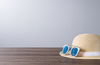 放在木质桌面上的草帽与太阳镜摆在灰色背景前