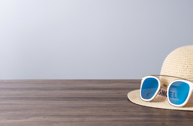 放在木质桌面上的草帽与太阳镜摆在灰色背景前