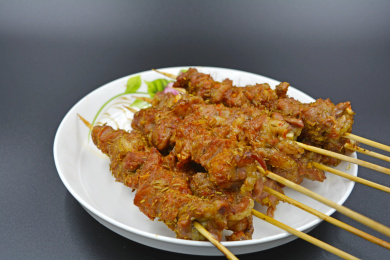 香喷喷的烤好的羊肉串，白色带花纹的瓷盘及灰色的台面